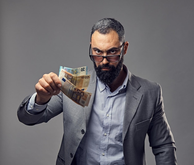 Free photo bearded male dressed in a suit catch money banknote in the air.