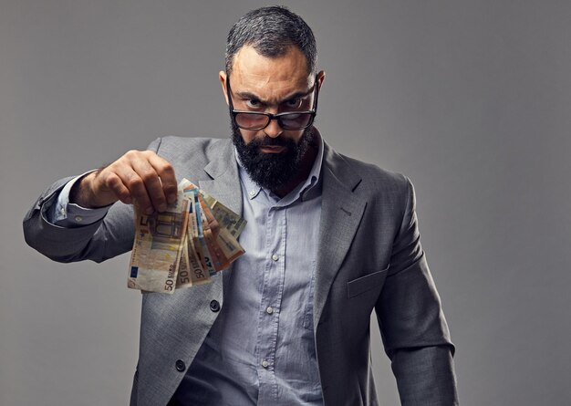 bearded male dressed in a suit catch money banknote in the air.