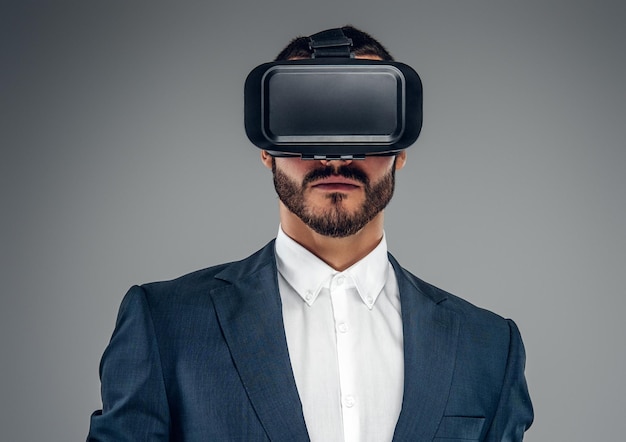 Free photo bearded male dressed in a suit with virtual reality glasses on his head.