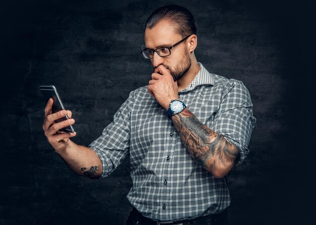 A bearded male in eyeglasses using smartphone.