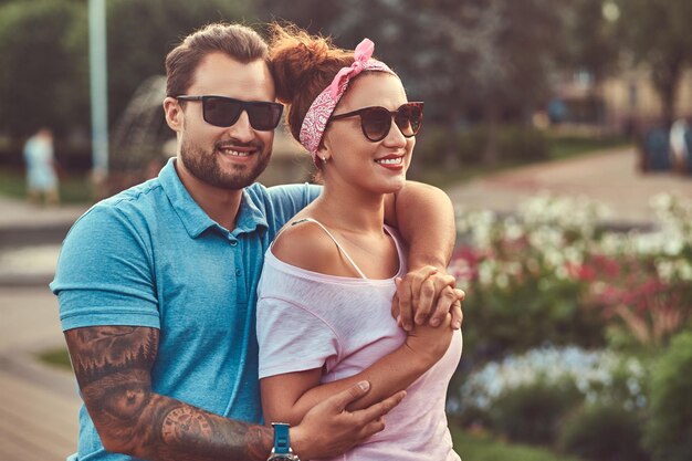 ひげを生やした男性は、公園に立っている間、彼の美しい赤毛の妻を抱きしめます。屋外でのデート中に幸せな中年カップル。