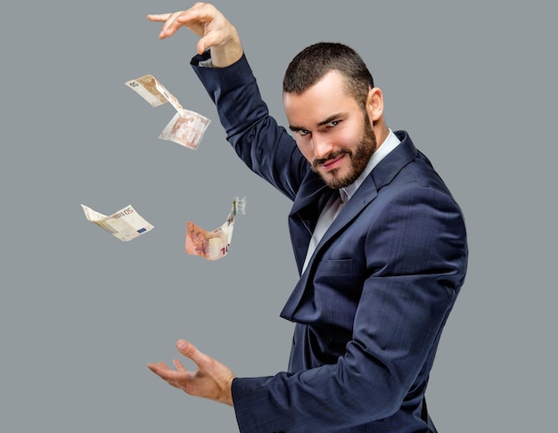 Бесплатное фото Бородатый мужчина в костюме с наличными деньгами, изолированными на сером фоне.
