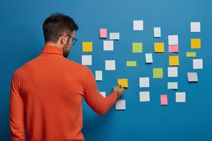 Free Photo bearded male organizing his tasks using sticky notes