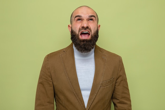 Бородатый мужчина в коричневом костюме смотрит вверх и кричит с агрессивным выражением лица