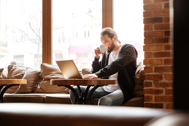 Bearded man in cafe with laptop and coffee