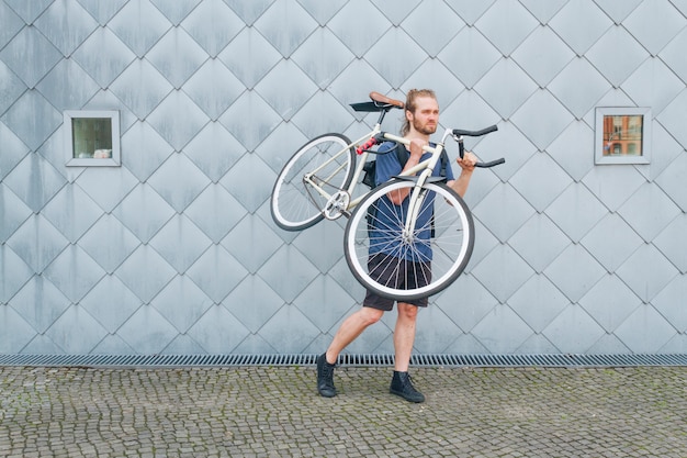 Bearded man carrying his bicycle at outdoors