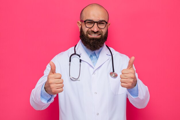 Bearded man doctor in white coat with stethoscope around neck wearing glasses looking smiling cheerfully showing thumbs up