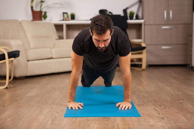 bearded man doing push ups on the floor of his house. Practice makes it better.