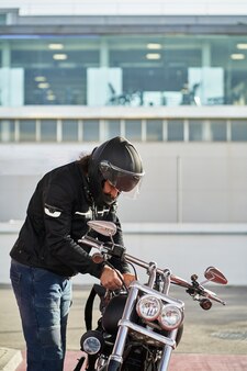 Бородатый мужчина заправляет мотоцикл