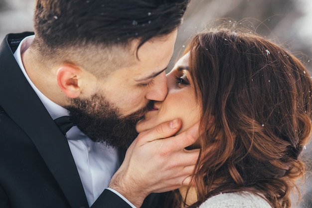 Foto gratuita l'uomo barbuto e la sua sposa adorabile posano sulla neve in una foresta magica di inverno