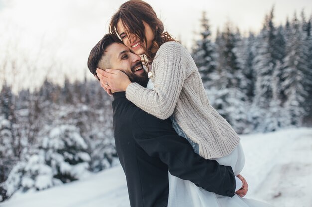 髭の男と彼の素敵な花嫁は魔法の冬の森の雪の上にポーズをとる