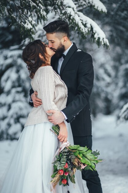 수염 난된 남자와 그의 사랑스러운 신부는 마법의 겨울 숲에서 눈에 포즈
