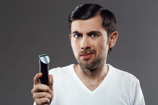 Bearded man holding razor, need shave bristle