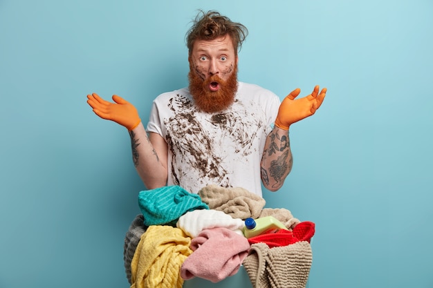 Free photo bearded man holds laundry basket, overwhelmed by household chores