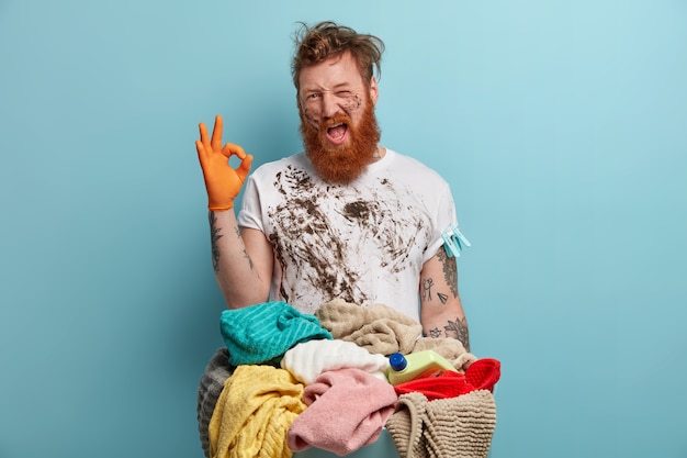 Bearded man holds laundry basket, overwhelmed by household chores