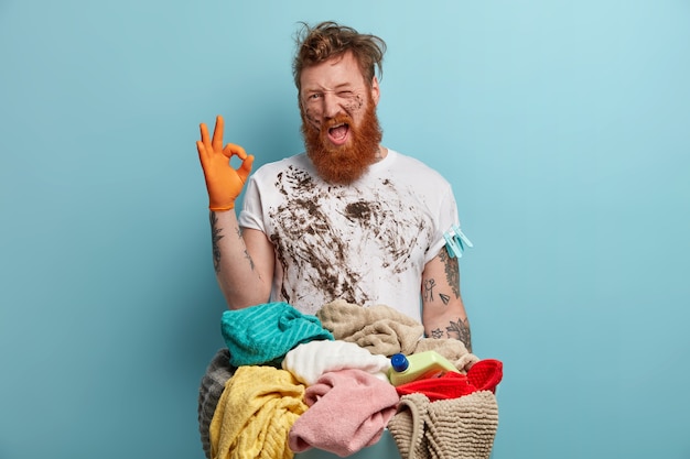 あごひげを生やした男は、家事に圧倒され、洗濯かごを持っています