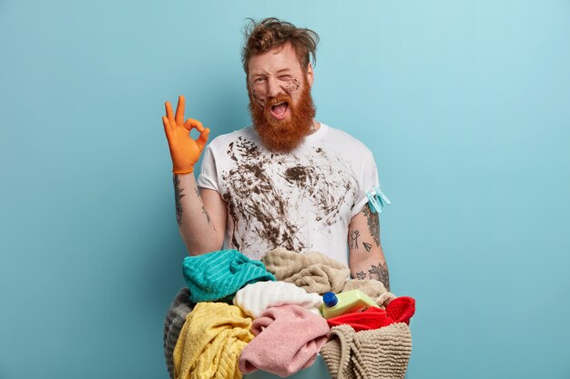 Bearded man holds laundry basket, overwhelmed by household chores