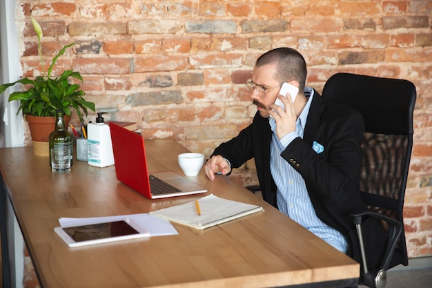 A bearded man in a jacket and without pants works at home in isolation. home Office