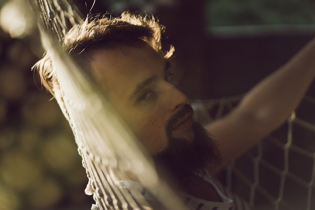 bearded man lying hammock on a warm summer day