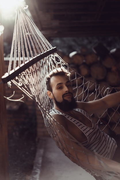 бородатый мужчина лежащий гамак в теплый летний день