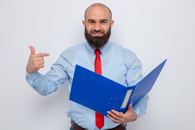 Bearded man in red tie and blue shirt holding office folder looking standing over white background