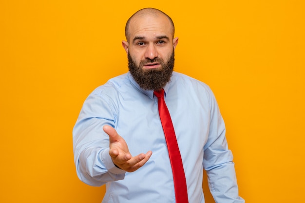 Bearded man in red tie and shirt looking raising arm like going to ask question