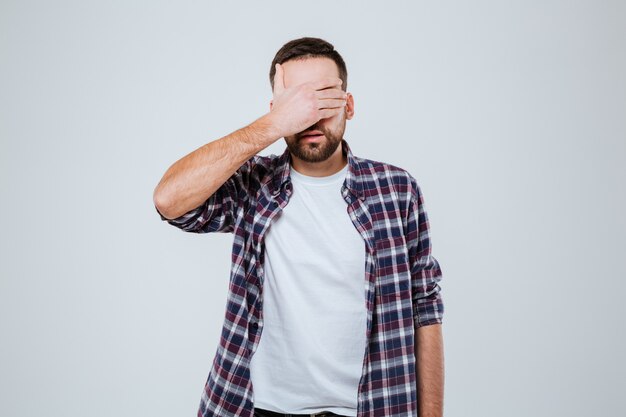 Bearded man in shirt covering his eyes