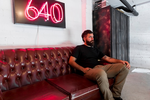 Bearded man sitting on couch in barbershop