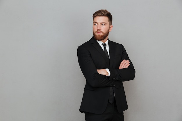 Bearded man in suit posing with crossed arms