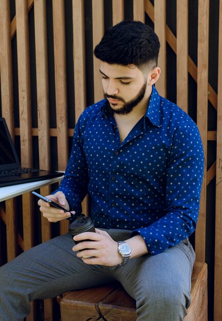 Bearded man surfing internet on smartphone while resting in cafe at daytime