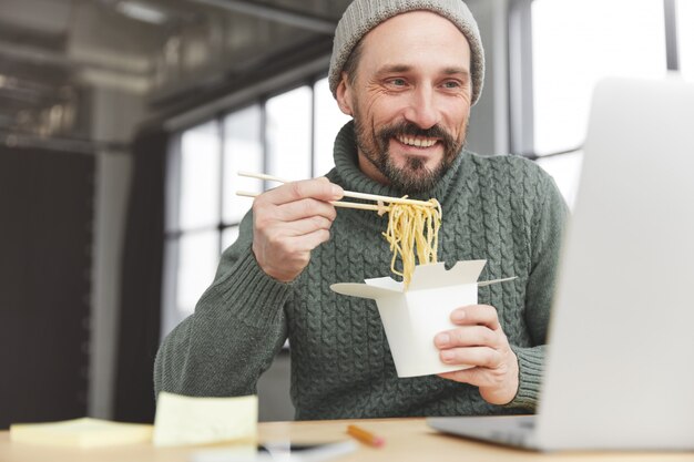 ニットの暖かいセーターと昼食の帽子を身に着けているひげを生やした男