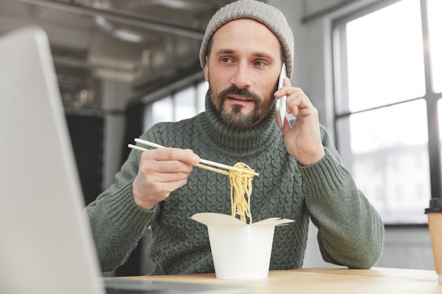 ニットの暖かいセーターと昼食の帽子を身に着けているひげを生やした男