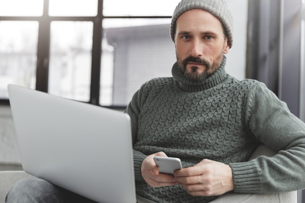 Uomo barbuto che indossa cappello e maglione caldo lavorato a maglia