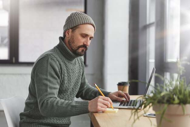 Bearded man wearing knitted warm sweater and hat