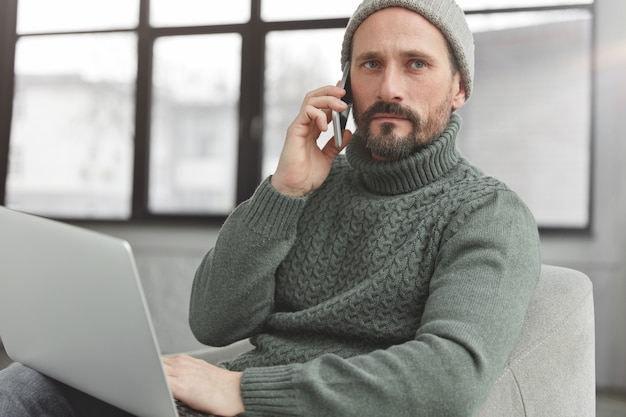 Uomo barbuto che indossa cappello e maglione caldo lavorato a maglia