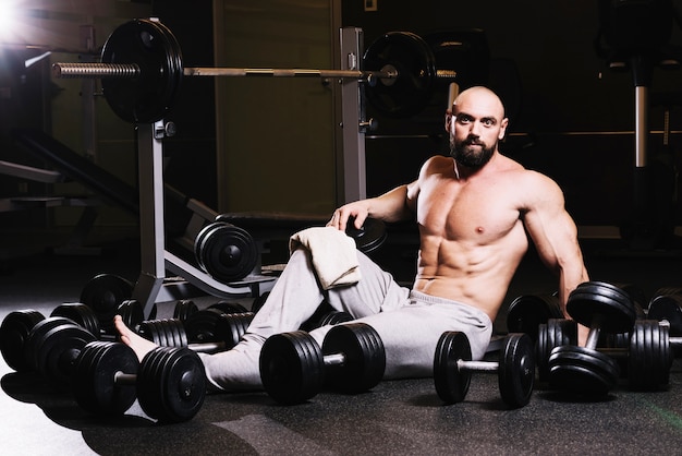 Bearded man with towel amidst dumbbells
