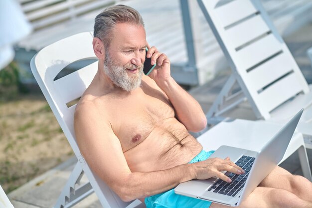 Bearded man working on a beach and having a phone call