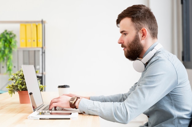 Uomo barbuto che lavora al computer portatile