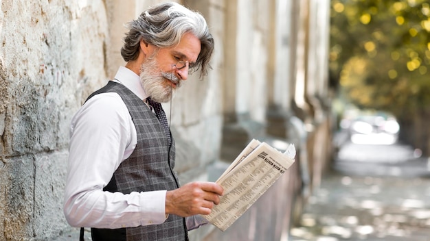 Бородатый зрелый мужчина читает газету