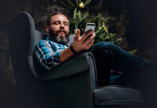 Bearded middle age male using smartphone over Christmas decorated background.