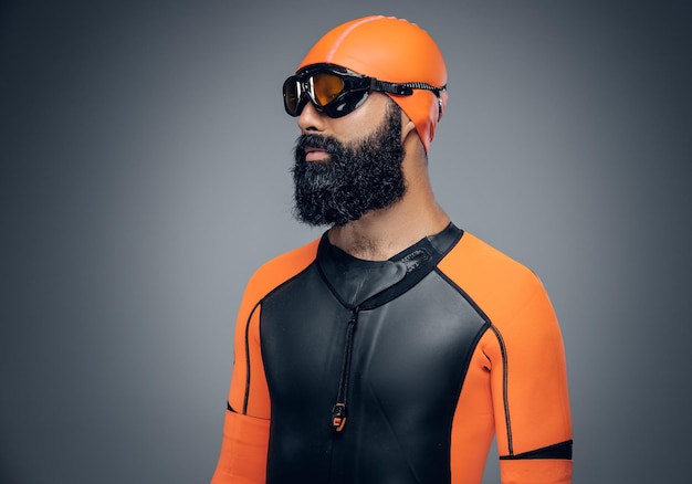 Bearded scuba diver male in orange neoprene suit isolated on grey background.