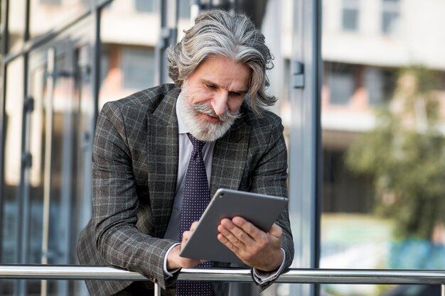 Free photo bearded senior male browsing tablet