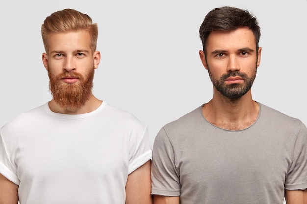 Bearded serious man friends with trendy haircut, stand close to each other, think where spend free time