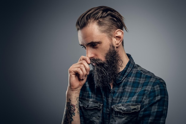 Bearded skinny man with tattooes feels dispair and sorrow while thinking about life.