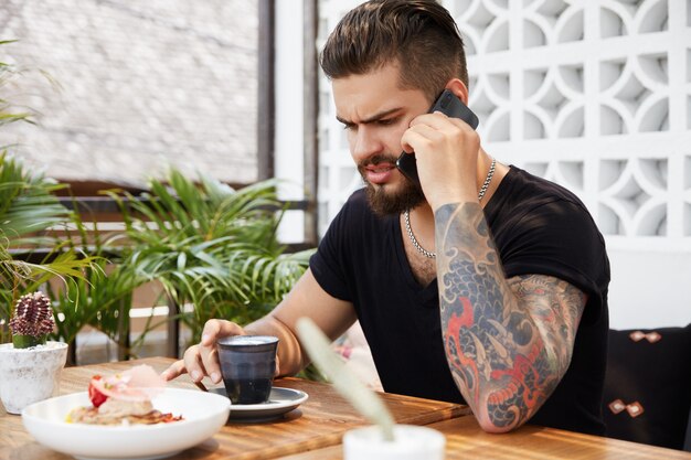 カフェに座っているひげを生やしたスタイリッシュな男