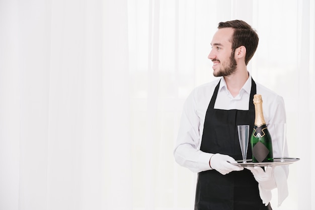 Bearded waiter with tray looking away