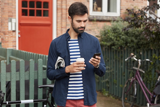 bearded young guy reads information on phone