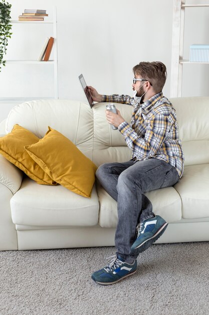 Bearded young man browsing tablet on the sofa