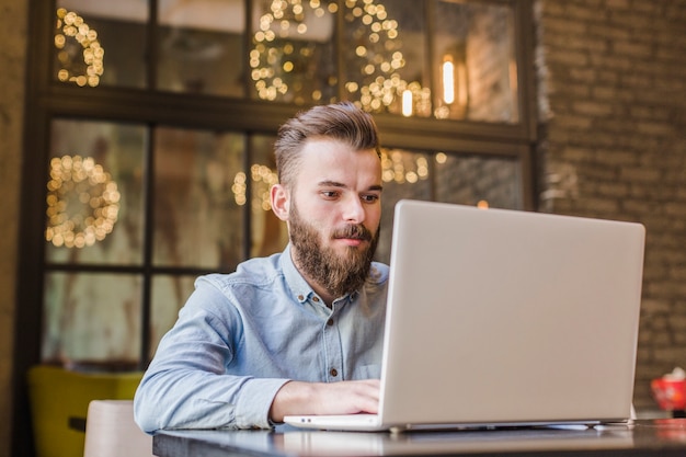 Free photo bearded young man working on laptop