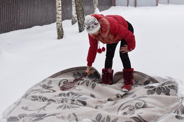 눈 속에서 겨울에 먼지에서 카펫을 치십시오. 눈으로 홈 카펫 청소. 카펫은 하얀 눈 위에 놓여 있다